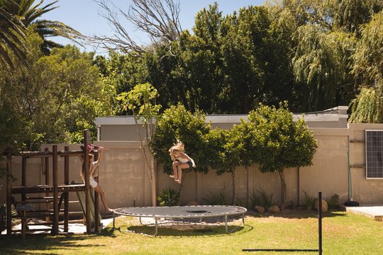 Girl Jumping On Trampoline In The Garden