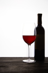 closeup view of bottle and glass with red wine on dark wooden table