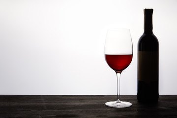 bottle and glass with red wine on dark wooden table