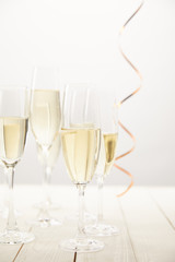 closeup view of champagne glasses with ribbon on white wooden table, holiday concept