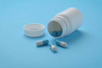 Container and capsules on blue background. Isolated