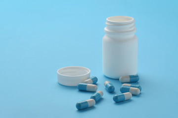 Container and capsules on blue background. Isolated