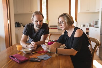 Couple calculating invoice bills in kitchen
