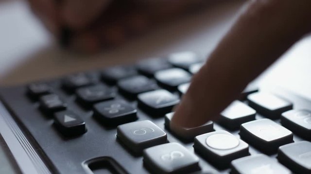 Man accountant hand holding pen counting on calculator. Businessman Doing Calculations