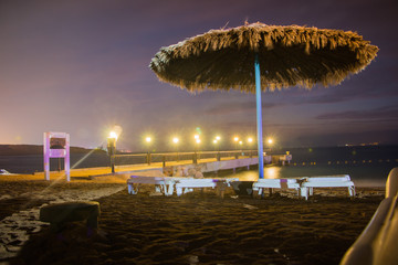 Beautiful evening in a summer night with a beach and umbrellas and colored light bright