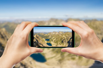 Fotografowanie górskich krajobrazów za pomocą smartphone. Dłonie trzymające telefon komórkowy. - obrazy, fototapety, plakaty