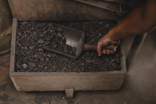 Blacksmith removing coals from box