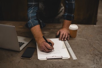 Blacksmith writing on a clipboard in workshop