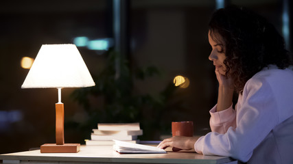 Mixed-race female student sitting in cafe and reading her diary, relax time