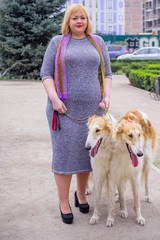 Plus size woman on a walk with dog of Russian hound greyhound breed. Pets and human, friends of...