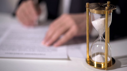 Closeup of sand clock measuring time, official signing important reform document