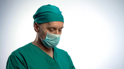 Fototapeta na wymiar Thoughtful male surgeon put on face mask before serious operation, concentrated