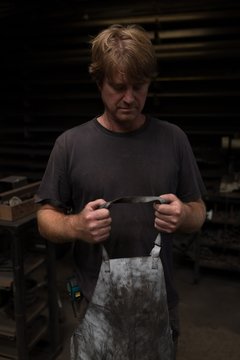 Blacksmith wearing apron in workshop