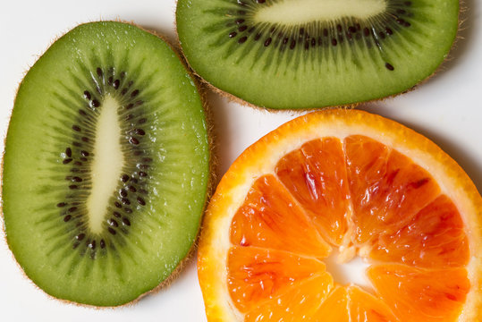 Close up of sliced kiwi and orange against white background
