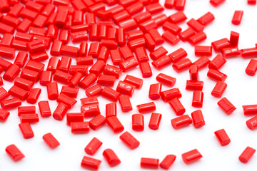 Red plastic polymer granules on white background.