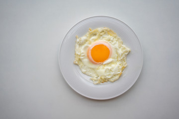 Fried egg on white ceramic dish or plate isolated on white background.