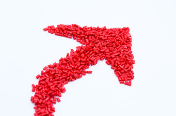 Red arrow design of plastic polymer granules isolated on white background