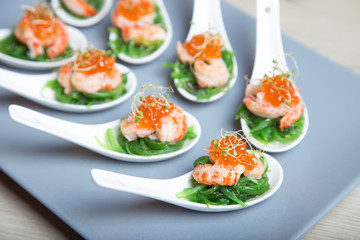 Appetizer from seaweed chuka, crabs and caviar on portioned spoos. Selective focus, close-up.