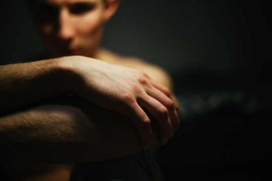 Portrait of a shirtless man hugging his knees