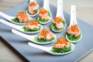 Appetizer from seaweed chuka, crabs and caviar on portioned spoos. Selective focus, close-up.