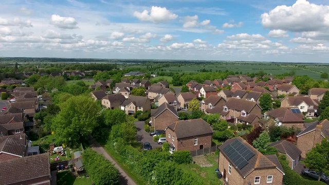 Camera panning down on the village, hamlet of Great Paxton Cambridgeshire England, with green fields, blue sky and clouds  