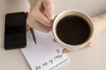 Top view of the goals list for the day, a Cup of coffee on a bright table.