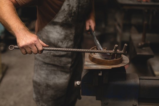 Blacksmith shaping a metal rod