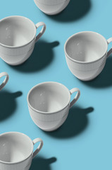 Pattern. Cup concept. Group of white cups on blue background. Creative style.