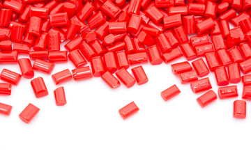 Red plastic polymer granules on white background.