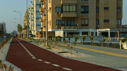 Empty jogging track in Cyprus city, hotels illuminated with evening sun, travel