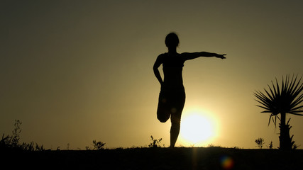 Silhouette of young woman stretching before doing exercises early morning