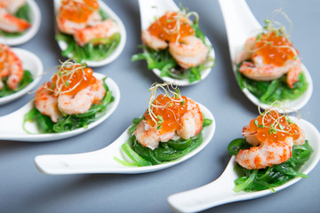 Appetizer from seaweed chuka, crabs and caviar on portioned spoos. Selective focus, close-up.