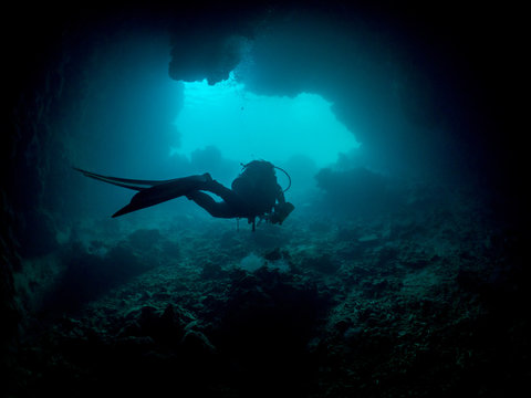 Woman swimming through an underwater cave, Koror, Palau