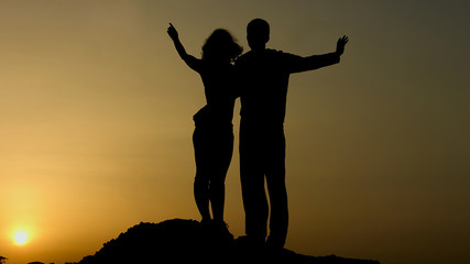 Silhouette of happy couple enjoying sunset together, looking in future with hope