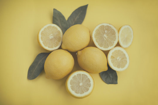 Close-up overhead view of whole and halved lemons on a yellow background