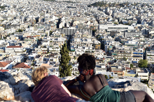 A romantic couple watching the panorama of Athens from Acropolis of Athens at sunset