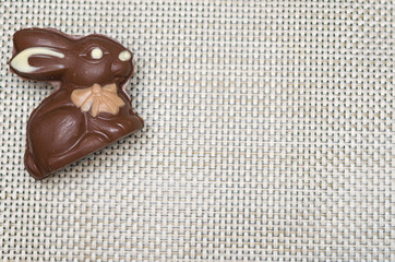 Concept of Easter, plush Easter bunny on straw background with decorated, colorful eggs.