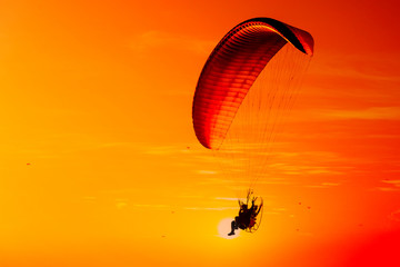 Silhouette of paraglider flying in the evening sky with sunset.