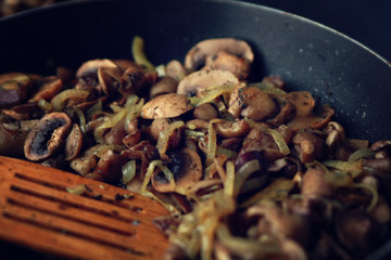 A skillet with a fried mushrooms. Vegan dish. Fried mushrooms and onion in the frying pan. European cuisine. Pan fried mushrooms. Simple vegetarian meal. Close up. Selective focus.