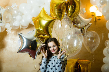 Little girl smile with golden silver star balloons, christmas. Happy child celebrate new year and xmas holidays. New year eve celebration. Party decor and design for birthday and anniversary