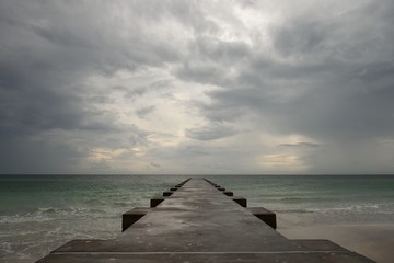 Low angle view of a long pier extending into the ocean with a cloudy and stormy sky, Gulf Coast of Florida