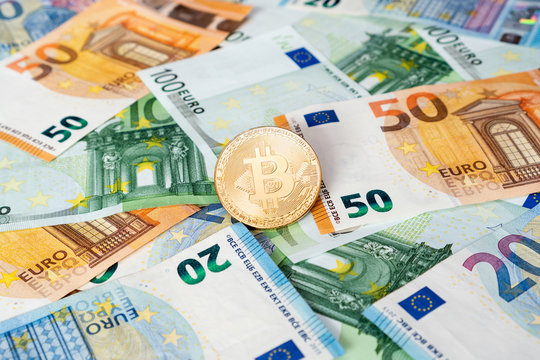 Gold Bitcoin coin on bills of euro banknotes