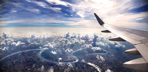 Obraz premium Pojęcie podróż samolotowa Latać nad miastem w kierunku miejsca przeznaczenia. Zachód słońca krajobraz nad chmurami.