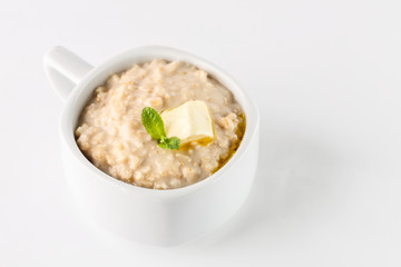 breakfast: oatmeal porridge with butter in white bowl on white background. Isolated