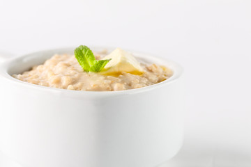 breakfast: oatmeal porridge with butter in white bowl on white background. Isolated