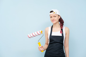 Girl painter, designer and worker paints a roller and brush the wall.