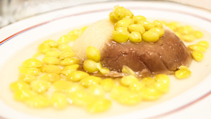 Selective focus Asian Thai Chinese sweet dessert menu, Chinese Henan hot sticky rice and steamed taro with yellow ginkgo nuts in sweet syrup in the dish on table background. Auspicious food served