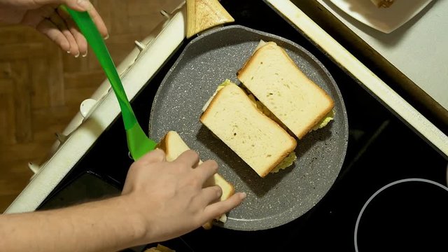 Closeup of hands prepare sandwiches in the kitchen. Fry three billets in a frying pan.