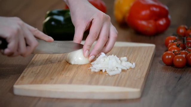 Woman chopping onions on cutting board with knife