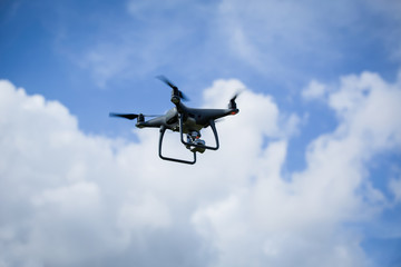 A flying drone hovering and isolated against a blue sky